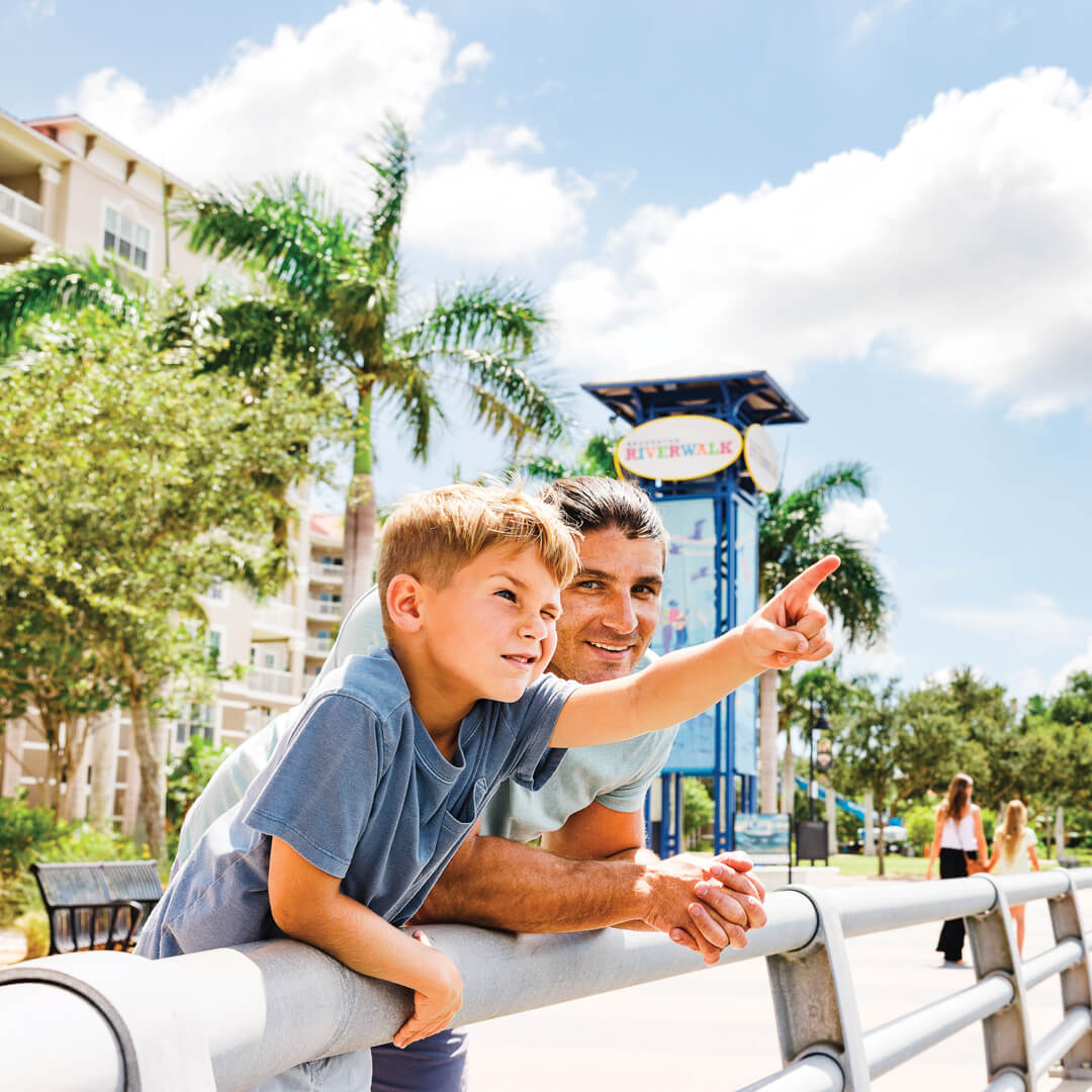 a man and son leaning on a railing on the Bradenton Riverwalk