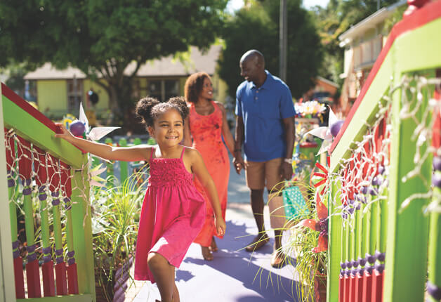 a girl in a pink dress and a man and woman walking down a sidewalk