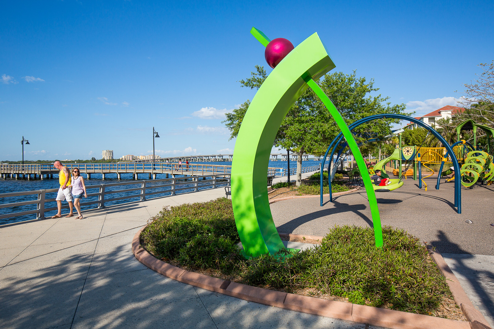 a green sculpture with a ball on top of it and a view of the Manatee RIver