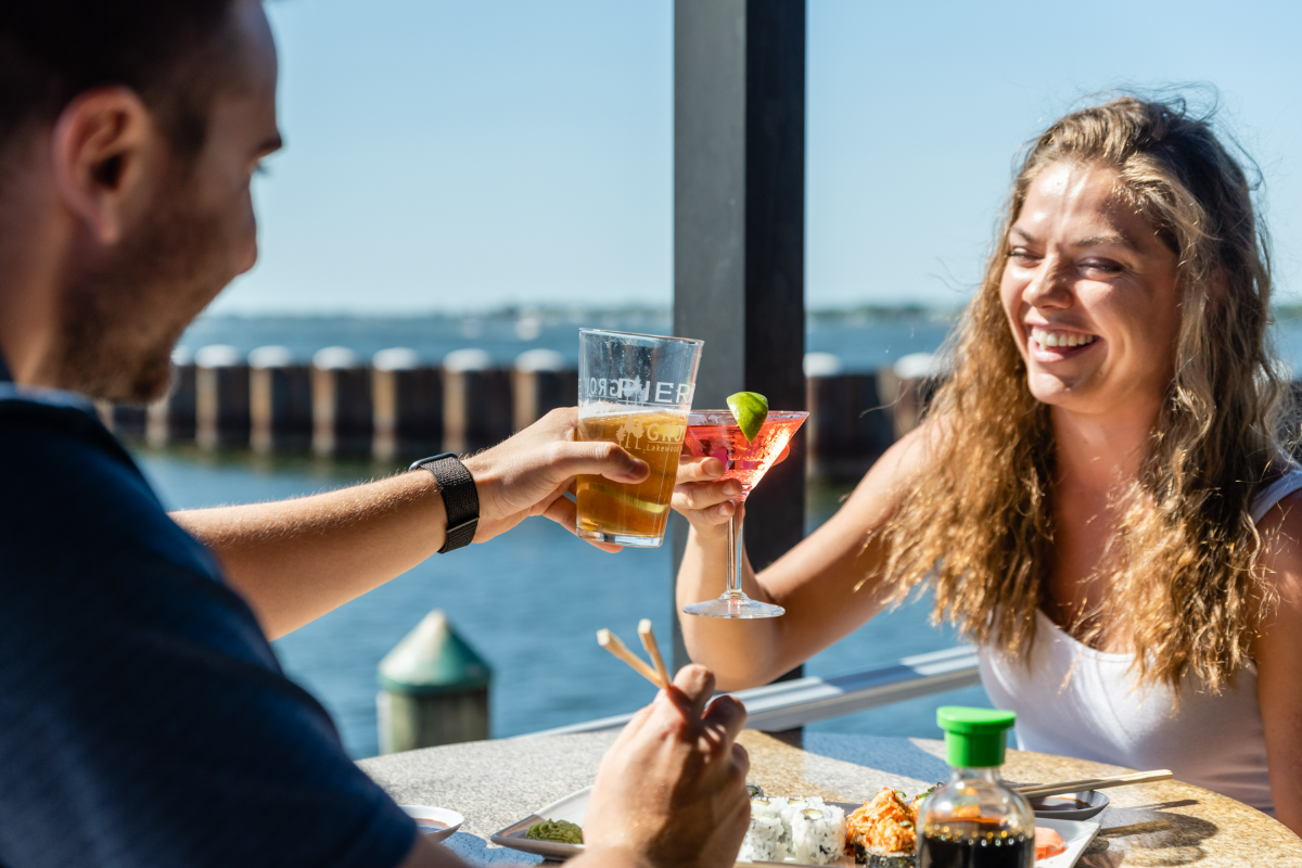 a man and woman holding drinks at Pier 22 with a view of the Manatee River